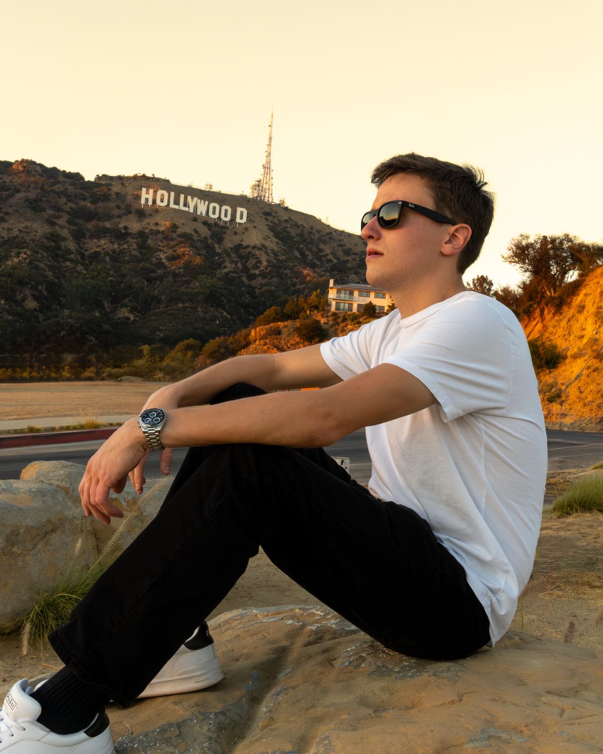 Christopher Spring sitting below the Hollywood sign at sunset